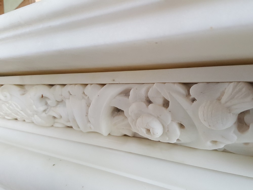 A carved white statuary marble Victorian fireplace surround featuring an ornate floral frieze and moulded arched jambs. View III