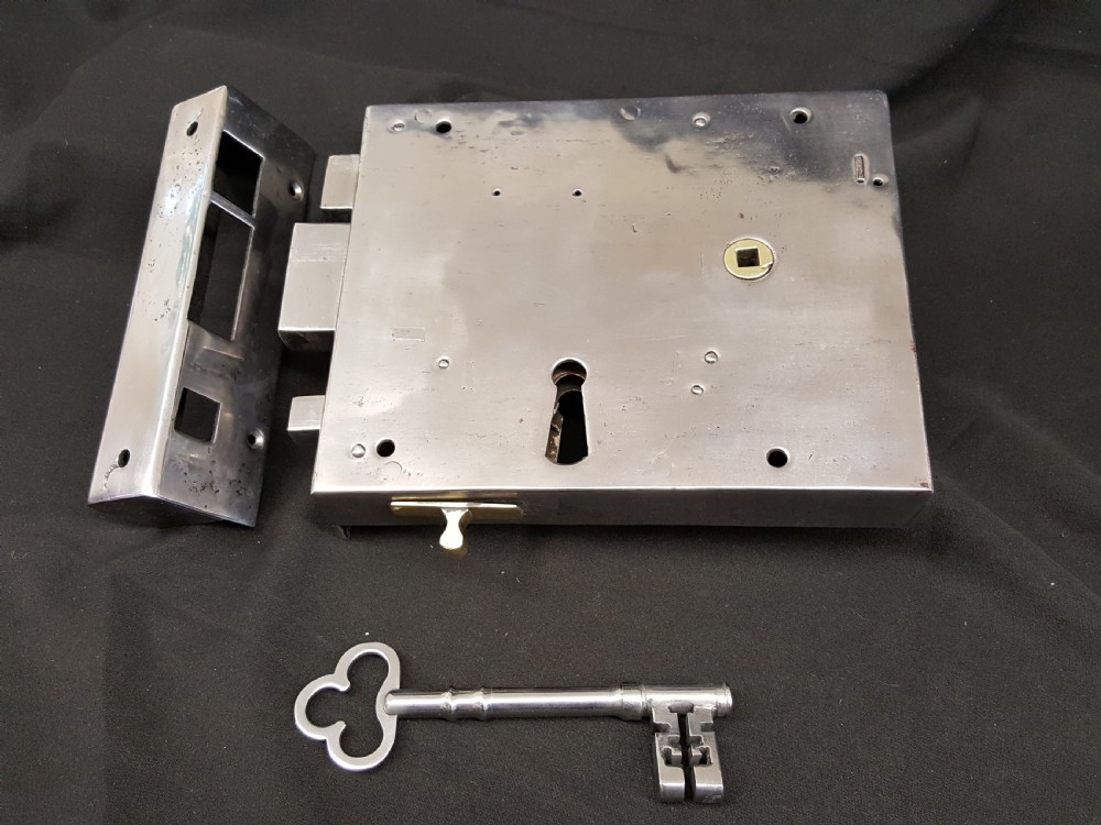 A polished steel Georgian rim box lock set shown with matching steel keep, skeleton key, and brass detail accents.