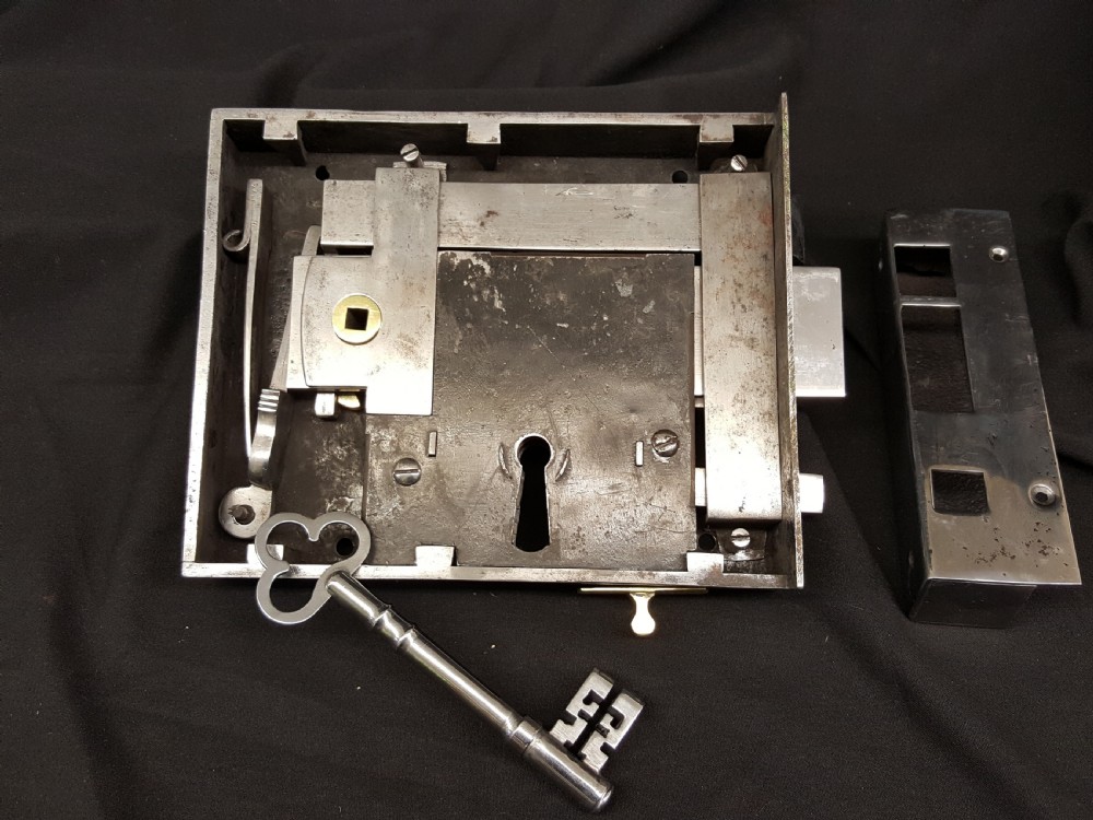 A polished steel Georgian rim box lock set shown with matching steel keep, skeleton key, and brass detail accents. View II