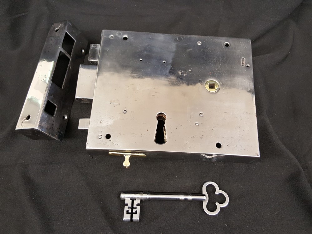 A polished steel Georgian rim box lock set shown with matching steel keep, skeleton key, and brass detail accents. View III