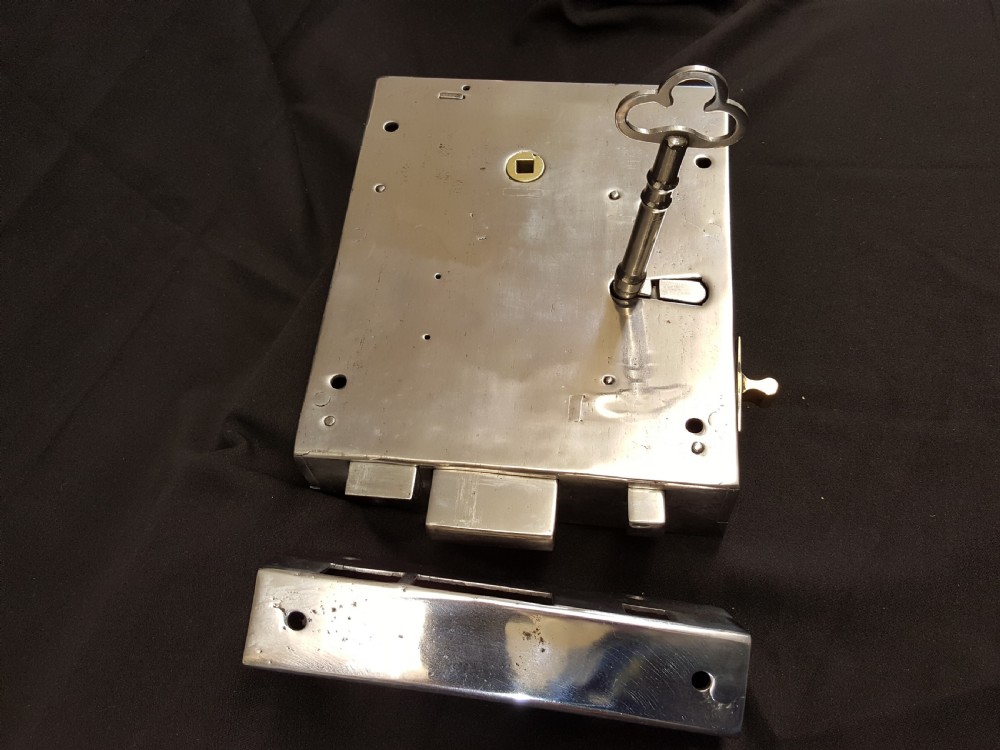 A polished steel Georgian rim box lock set shown with matching steel keep, skeleton key, and brass detail accents. View IV