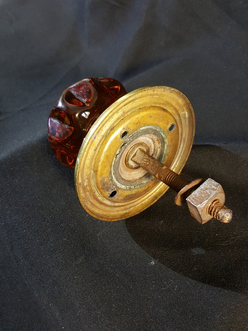 A Victorian amber glass door knob with a faceted profile mounted on a circular stepped brass backplate. View II