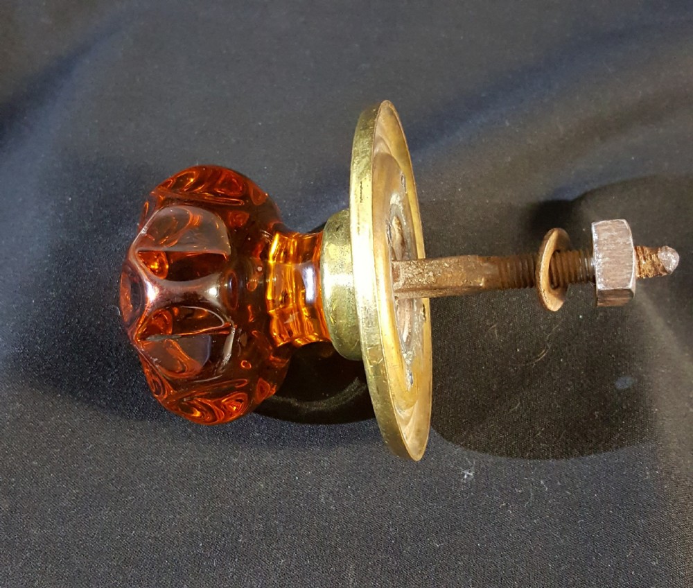 A Victorian amber glass door knob with a faceted profile mounted on a circular stepped brass backplate. View III