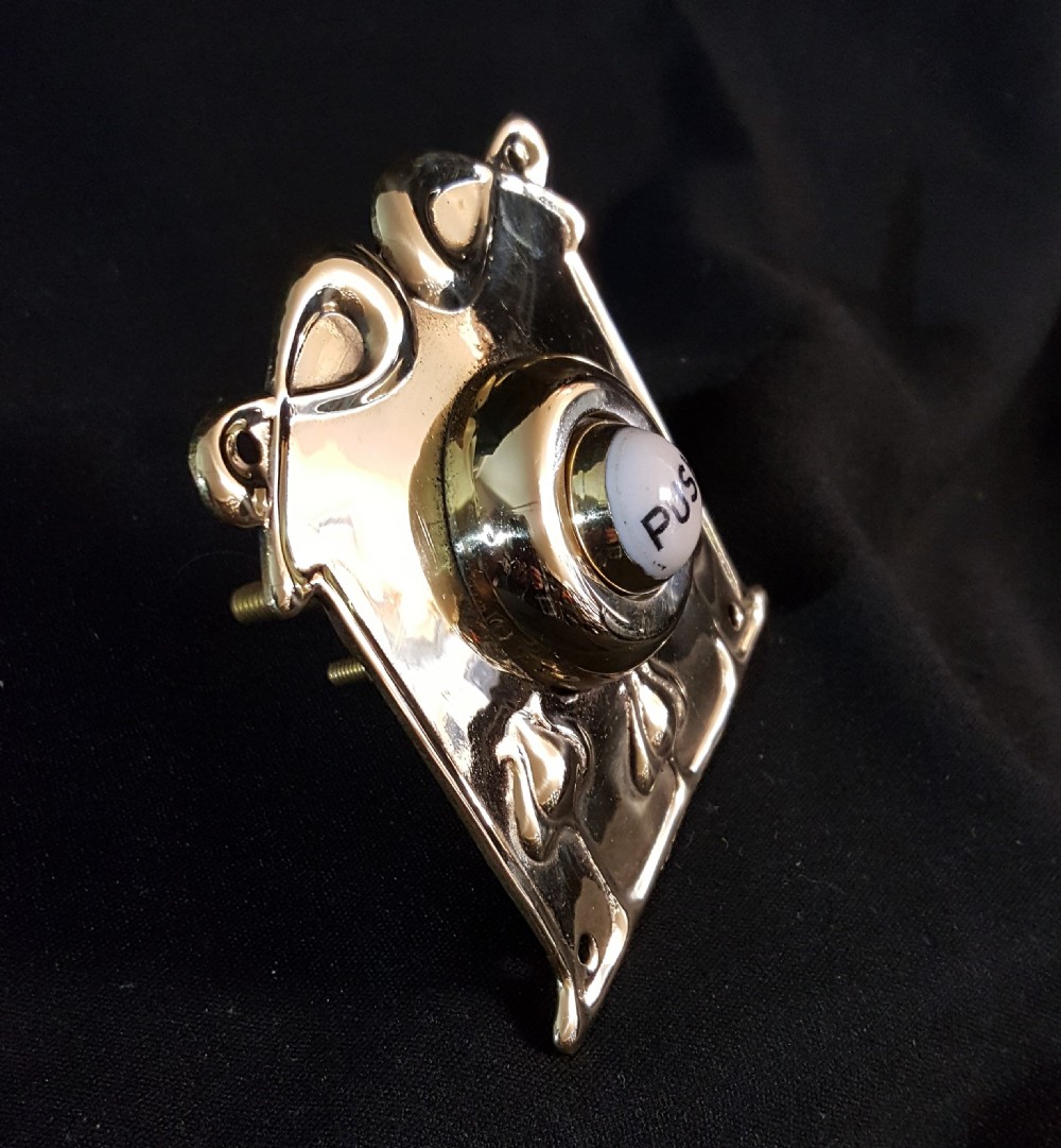 A square polished brass Art Nouveau bell push featuring stylised botanical relief motifs and a central white porcelain button with the word PUSH printed in black. View III