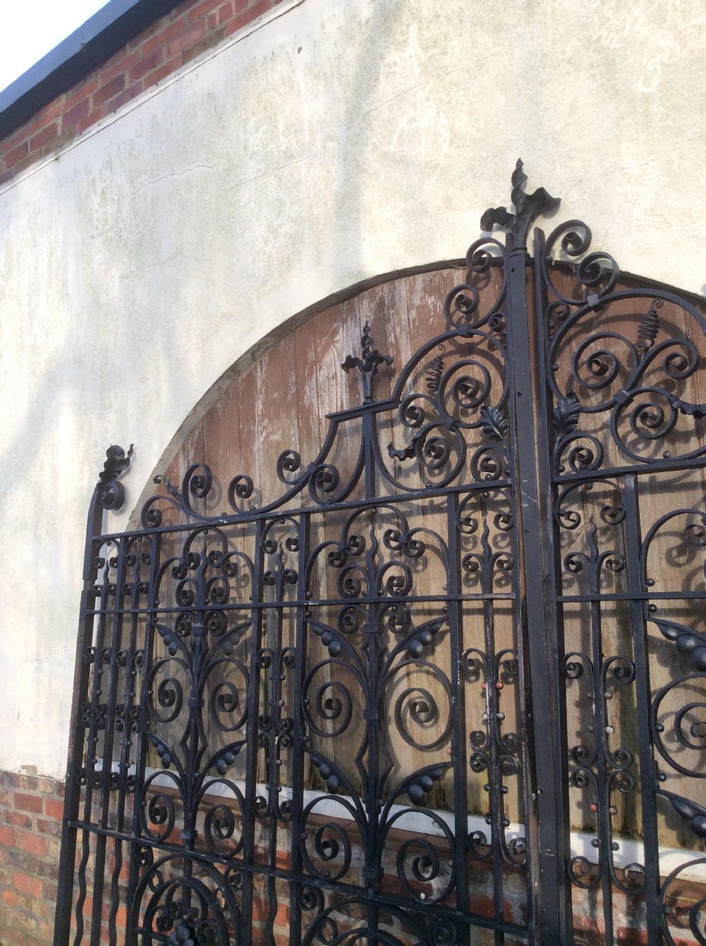 A pair of large black Victorian wrought iron driveway gates featuring ornate scrollwork, circular medallions, and decorative top finials. View III