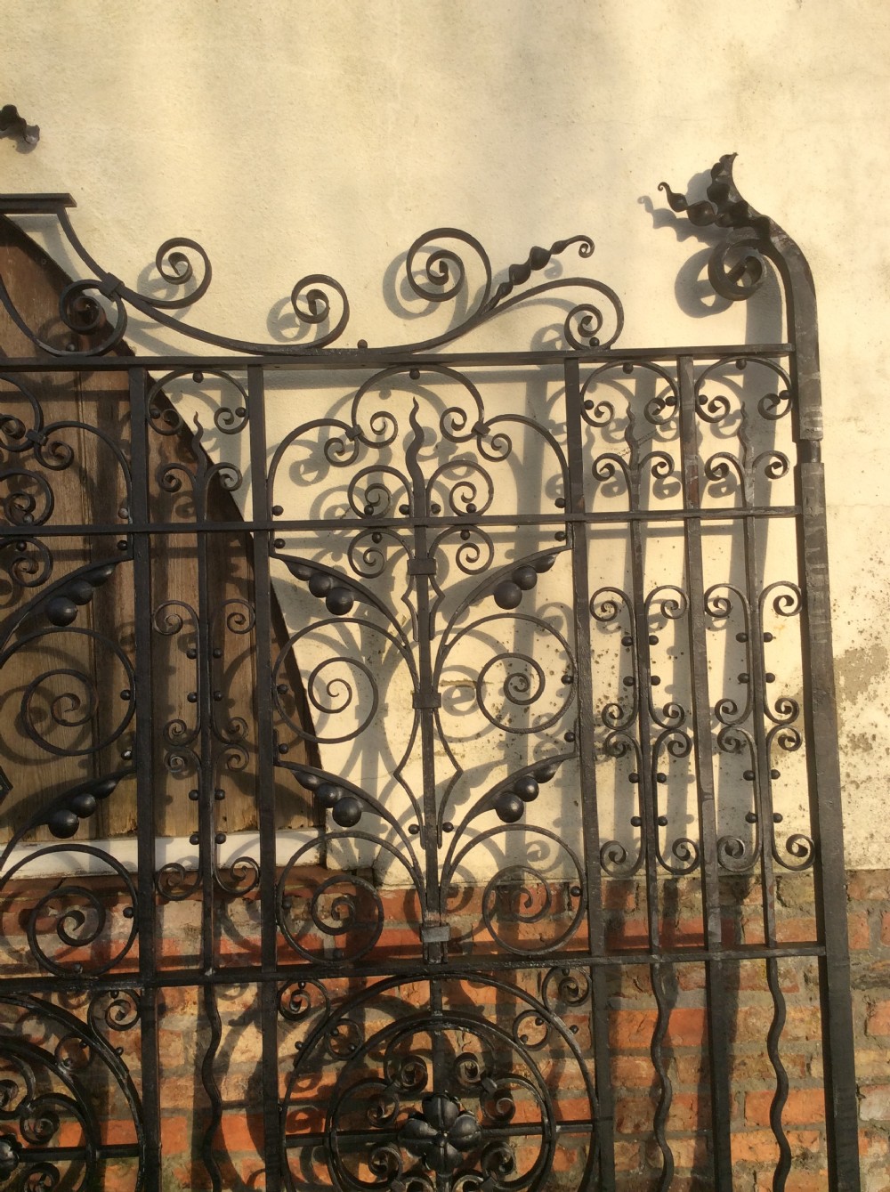 A pair of large black Victorian wrought iron driveway gates featuring ornate scrollwork, circular medallions, and decorative top finials. View IV