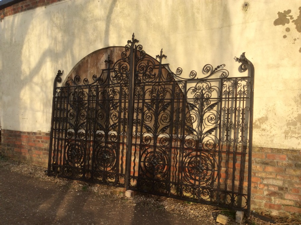 A pair of large black Victorian wrought iron driveway gates featuring ornate scrollwork, circular medallions, and decorative top finials. View V