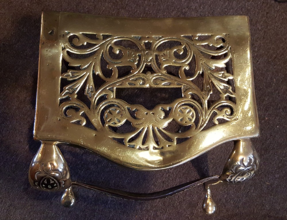 A Georgian pierced brass hearth footman featuring acanthus foliage scrollwork, side carrying handles, and shaped front cabriole legs. View V