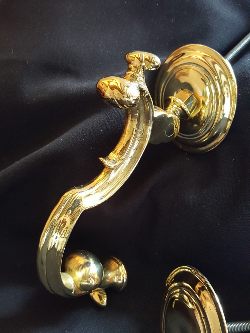 A polished brass Doctors style door knocker featuring an S-shaped handle and threaded mounting bolts. View II