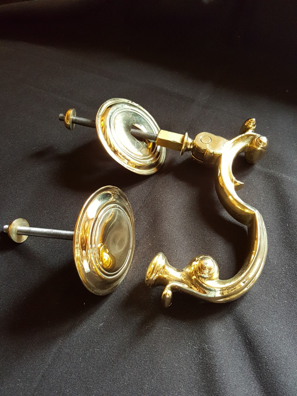 A polished brass Doctors style door knocker featuring an S-shaped handle and threaded mounting bolts. View III