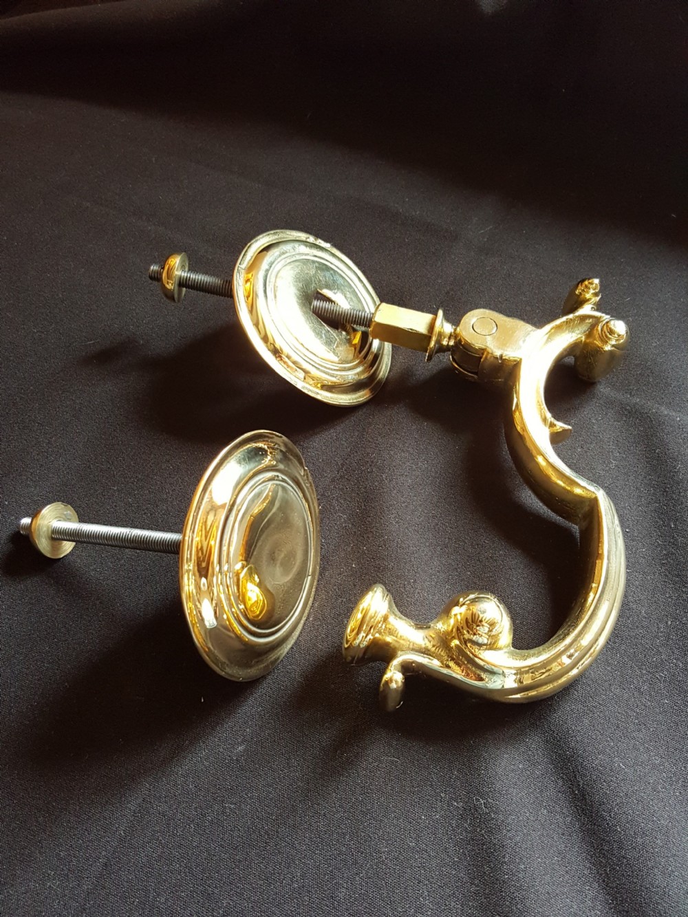 A polished brass Doctors style door knocker featuring an S-shaped handle and threaded mounting bolts. View IV