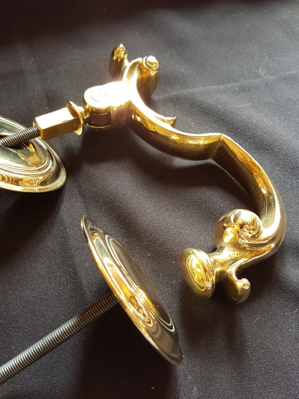A polished brass Doctors style door knocker featuring an S-shaped handle and threaded mounting bolts. View V