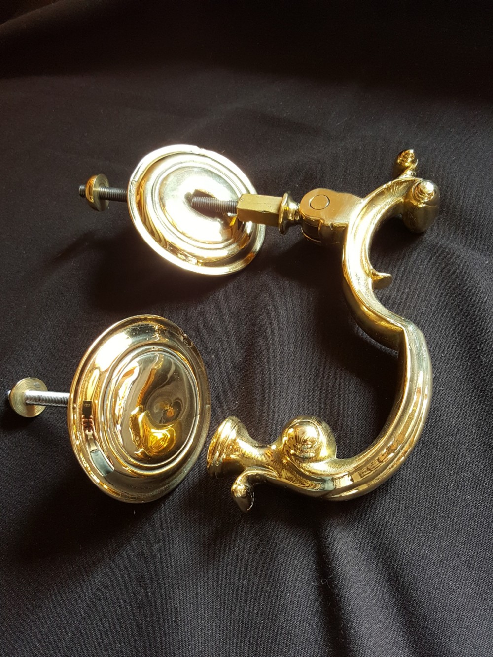 A polished brass Doctors style door knocker featuring an S-shaped handle and threaded mounting bolts. View VI