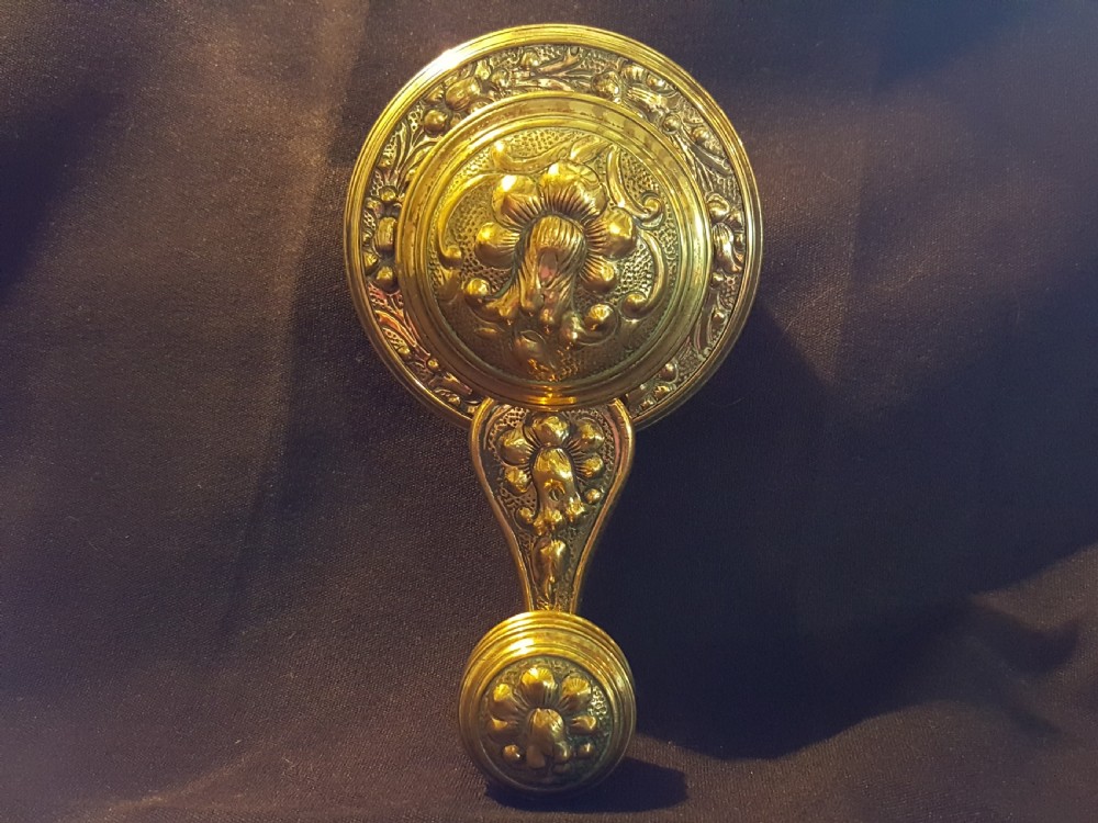 An ornate Victorian brass bell ringer featuring elaborate embossed floral patterns and a mechanical turn lever. View II