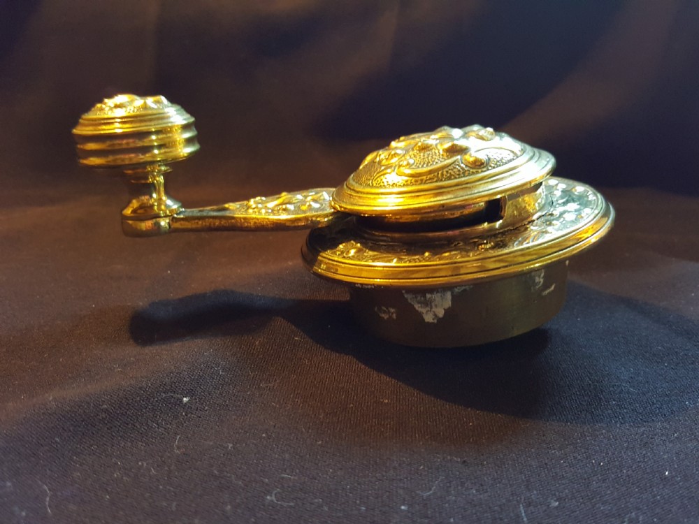 An ornate Victorian brass bell ringer featuring elaborate embossed floral patterns and a mechanical turn lever. View III