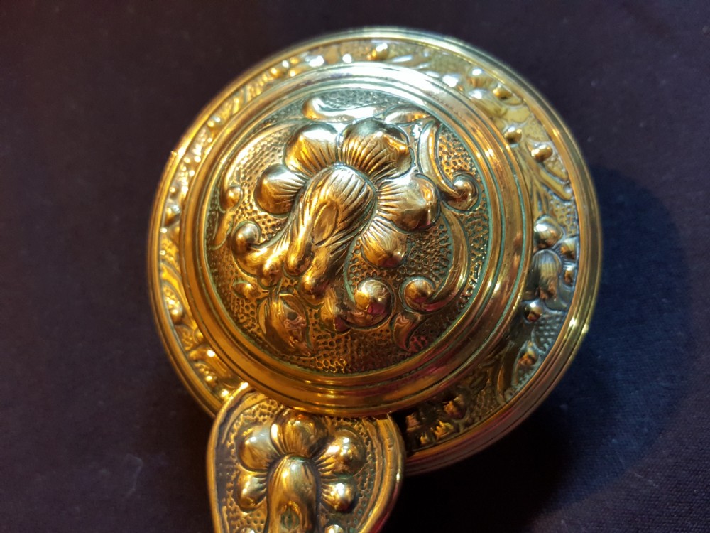 An ornate Victorian brass bell ringer featuring elaborate embossed floral patterns and a mechanical turn lever. View V