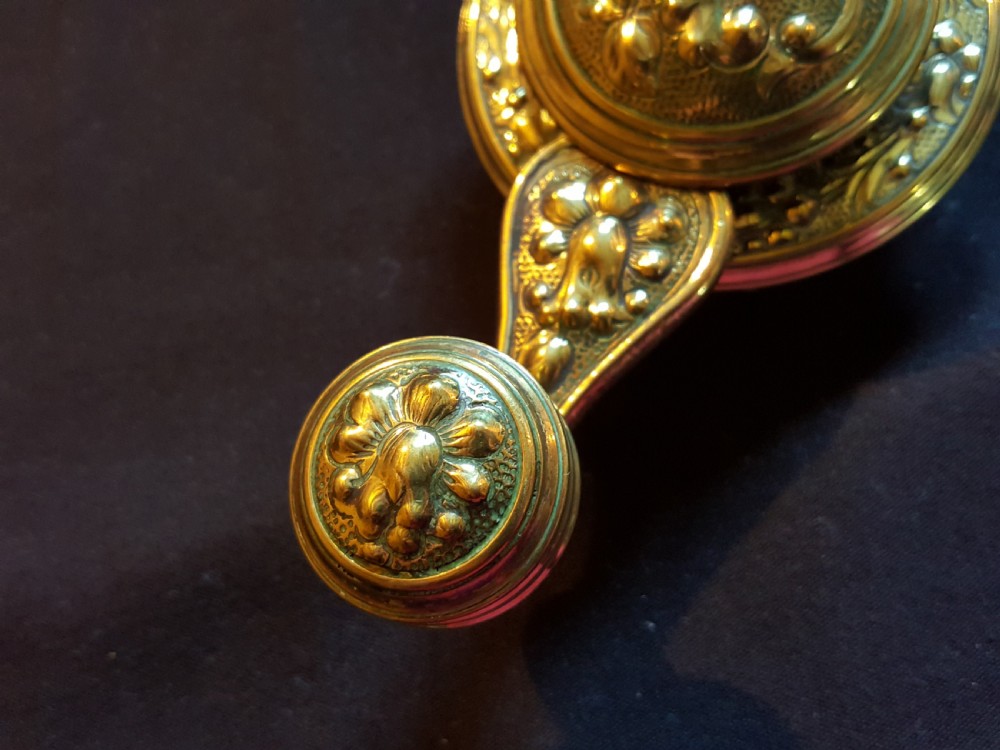 An ornate Victorian brass bell ringer featuring elaborate embossed floral patterns and a mechanical turn lever. View VI
