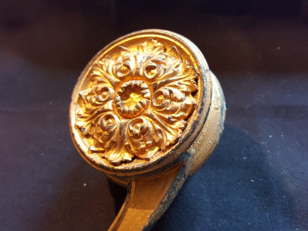 An ornate Georgian gilt brass mechanical bell pull featuring a circular carved floral rosette and a curved lever arm. View V