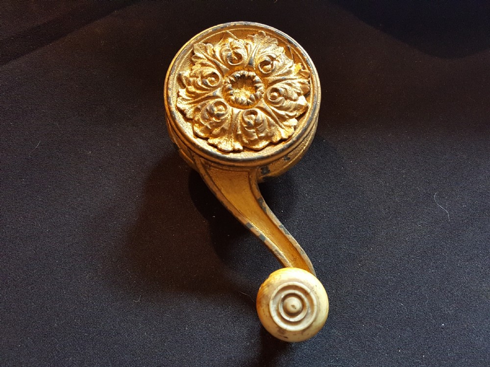 An ornate Georgian cast brass servant bell lever featuring a carved leaf rosette backplate and a turned horn handle.