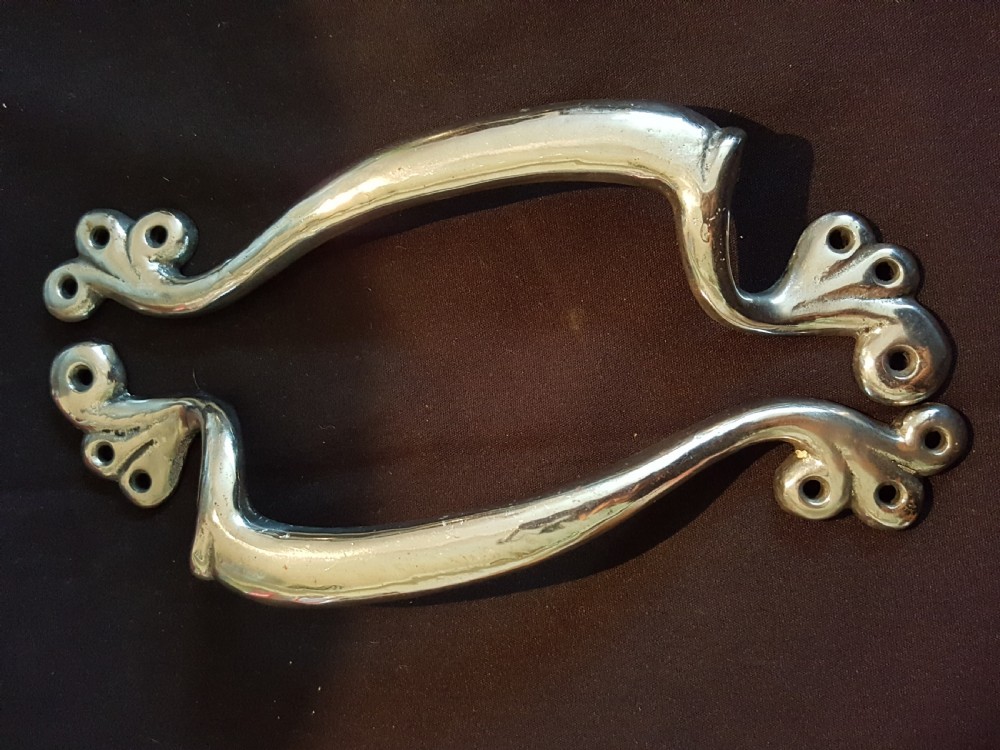 A pair of polished metal Art Nouveau door pull handles featuring curved whiplash forms with scrolled mounting plates. View II