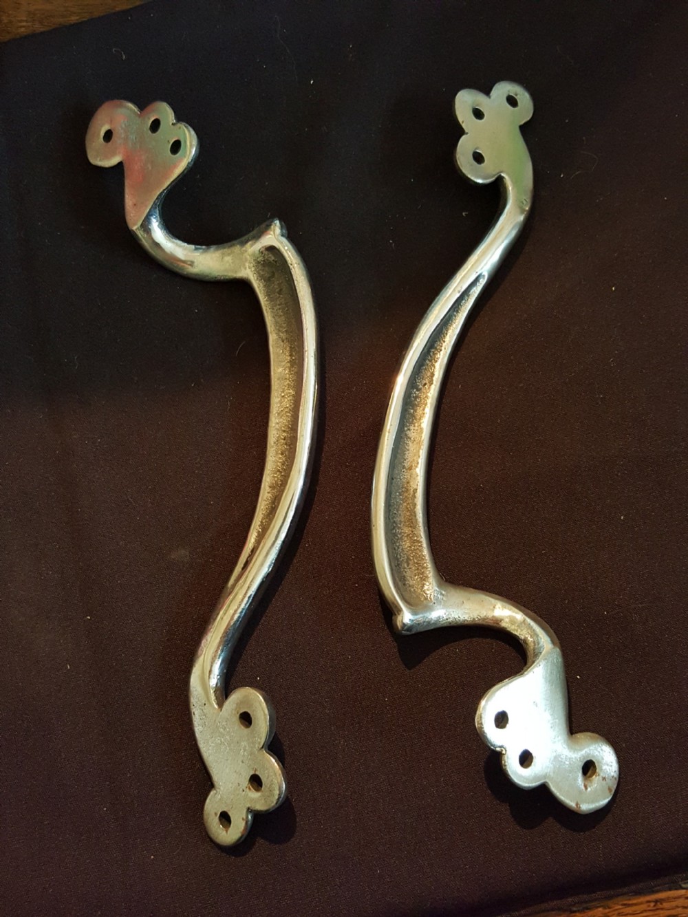 A pair of polished metal Art Nouveau door pull handles featuring curved whiplash forms with scrolled mounting plates. View III