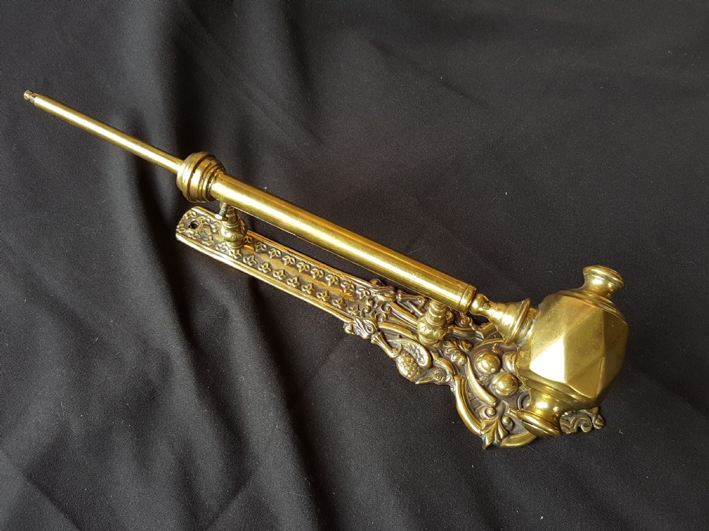 An ornate Victorian solid brass mechanical door bell pull featuring a faceted knob, rod lever mechanism, and cast foliate backplate.