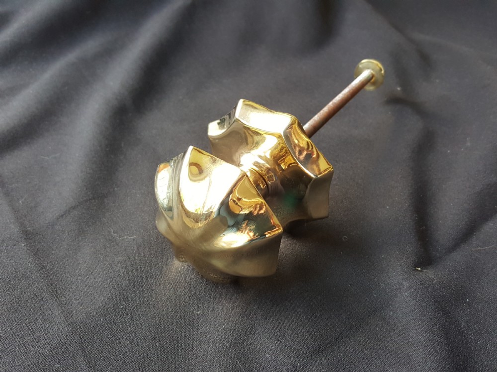 A polished brass centre door knob featuring a multi-fluted star shape with an attached threaded mounting bolt. View II