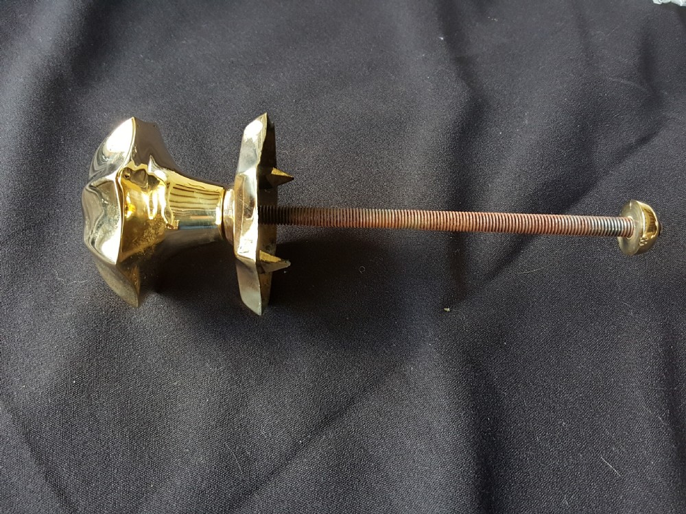 A polished brass centre door knob featuring a multi-fluted star shape with an attached threaded mounting bolt. View III