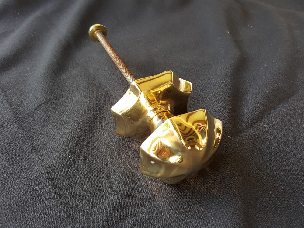 A polished brass centre door knob featuring a multi-fluted star shape with an attached threaded mounting bolt. View IV