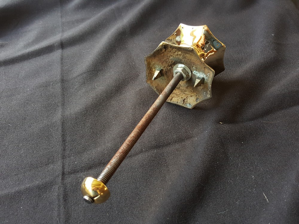 A polished brass centre door knob featuring a multi-fluted star shape with an attached threaded mounting bolt. View V