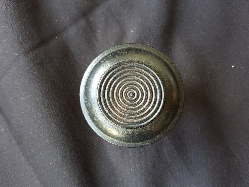 A Victorian centre door knob featuring a turned black ebony head with concentric circular grooves attached to a scalloped brass rose. View II