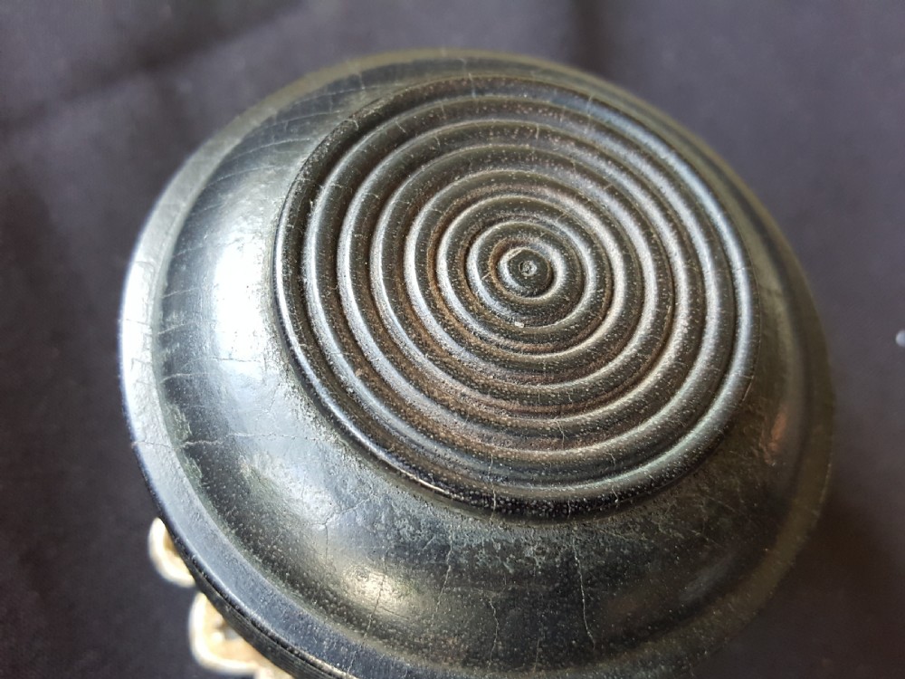 A Victorian centre door knob featuring a turned black ebony head with concentric circular grooves attached to a scalloped brass rose. View III