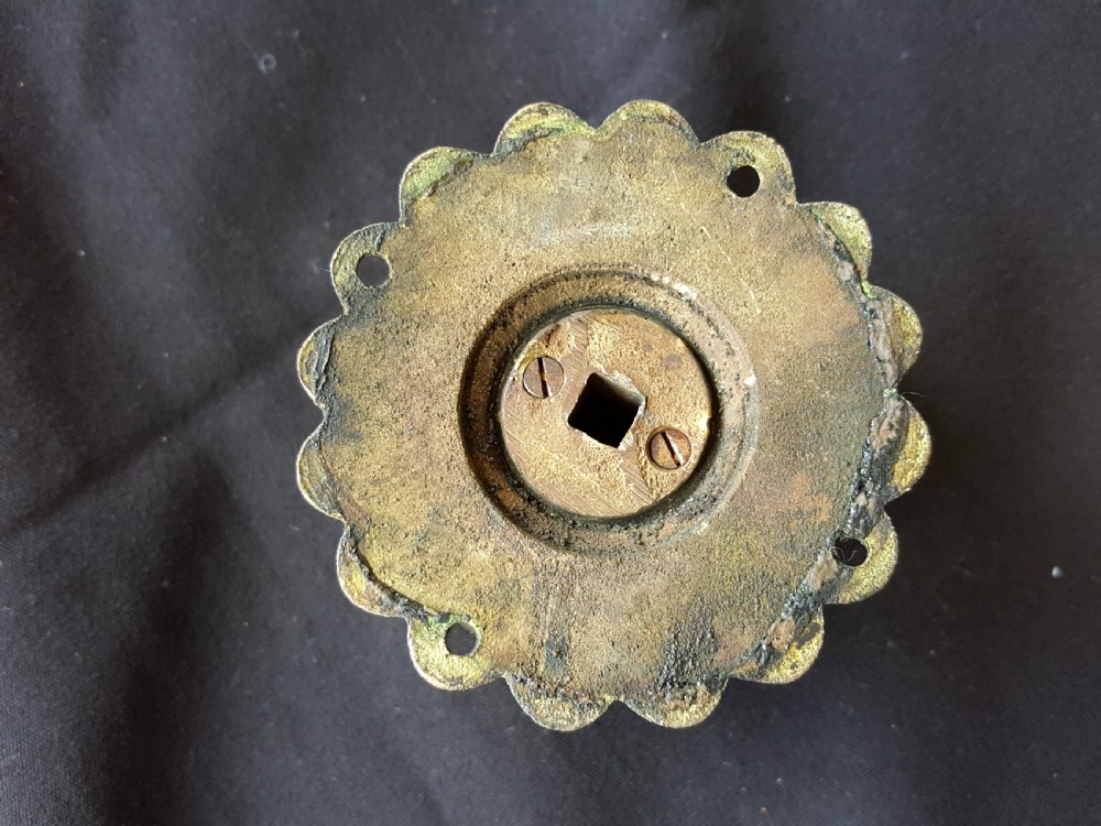 A Victorian centre door knob featuring a turned black ebony head with concentric circular grooves attached to a scalloped brass rose. View VI