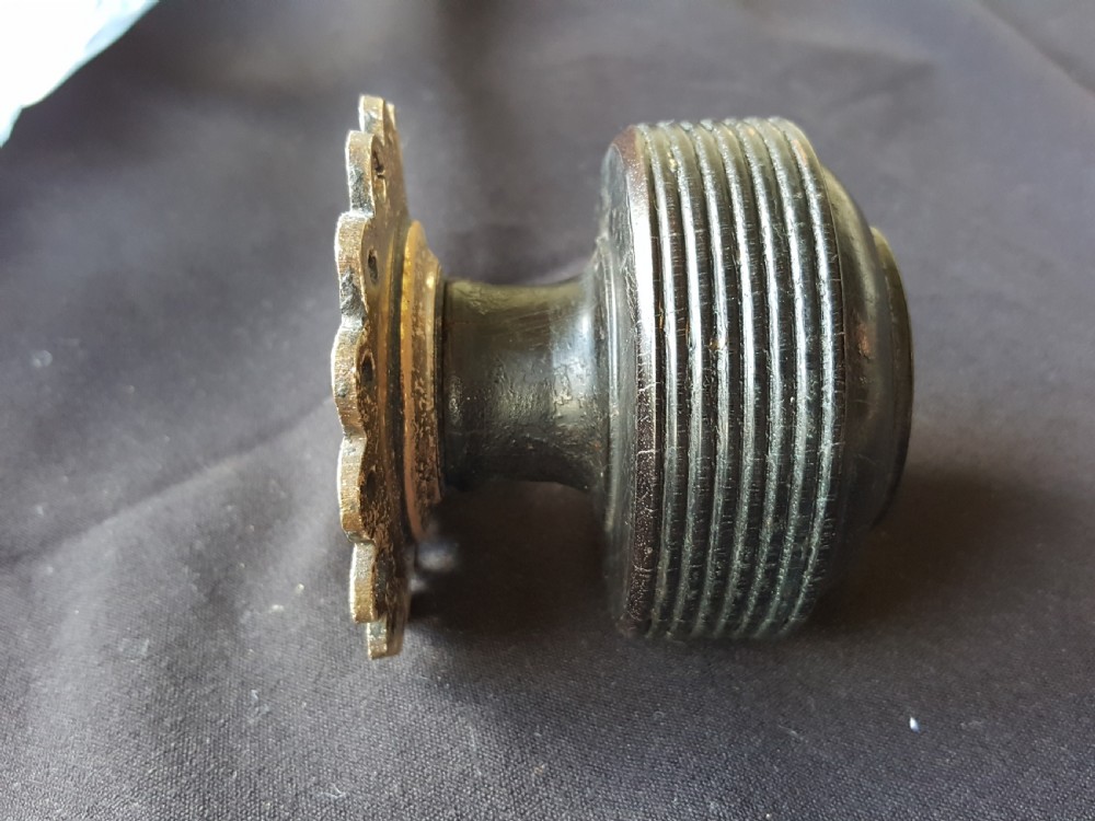 A Victorian centre door knob featuring a turned black ebony head with concentric circular grooves attached to a scalloped brass rose. View VII