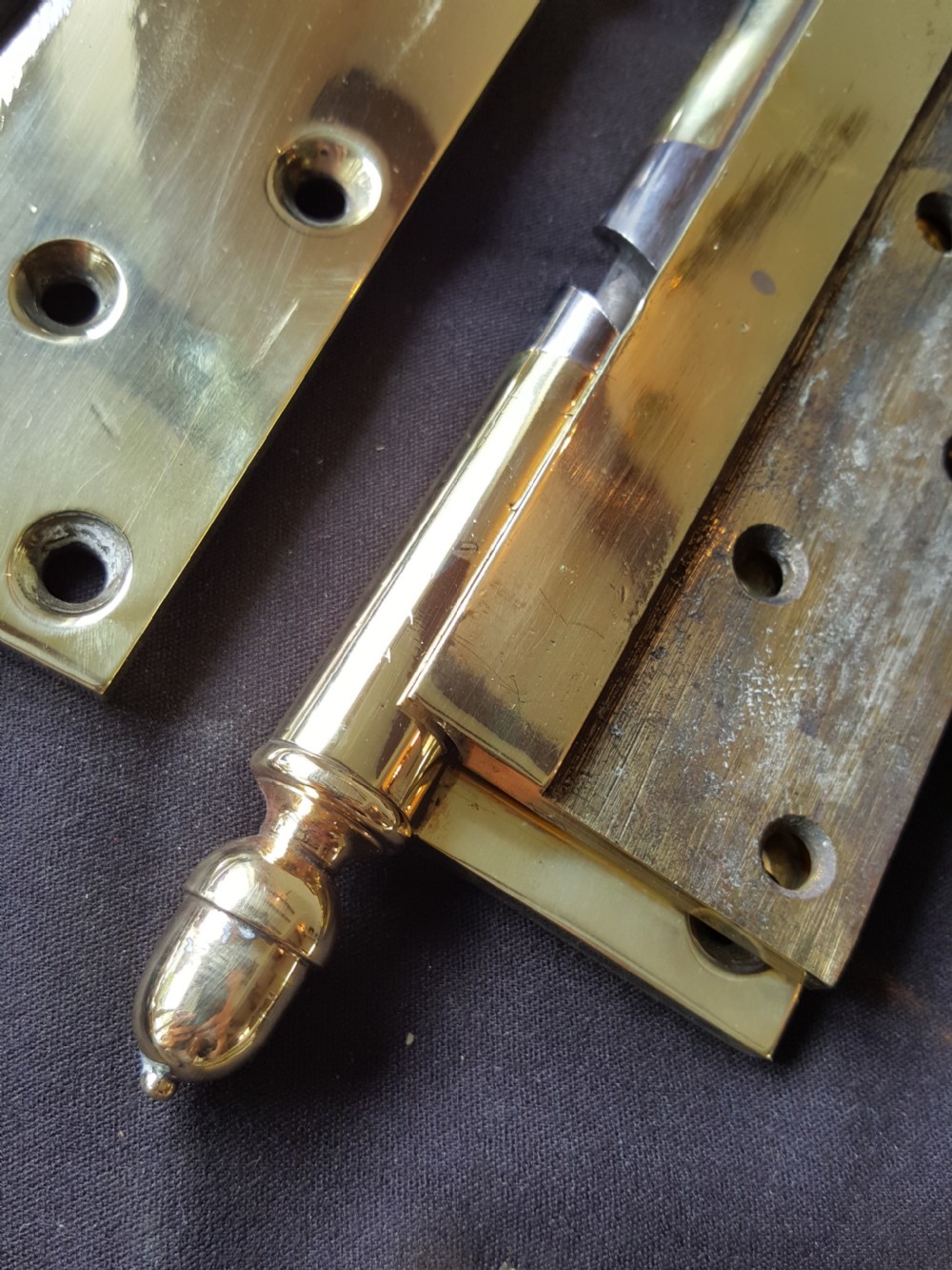 A set of four heavy cast brass Victorian door hinges featuring decorative acorn finials and pre-drilled countersunk screw holes with natural patina. View IV