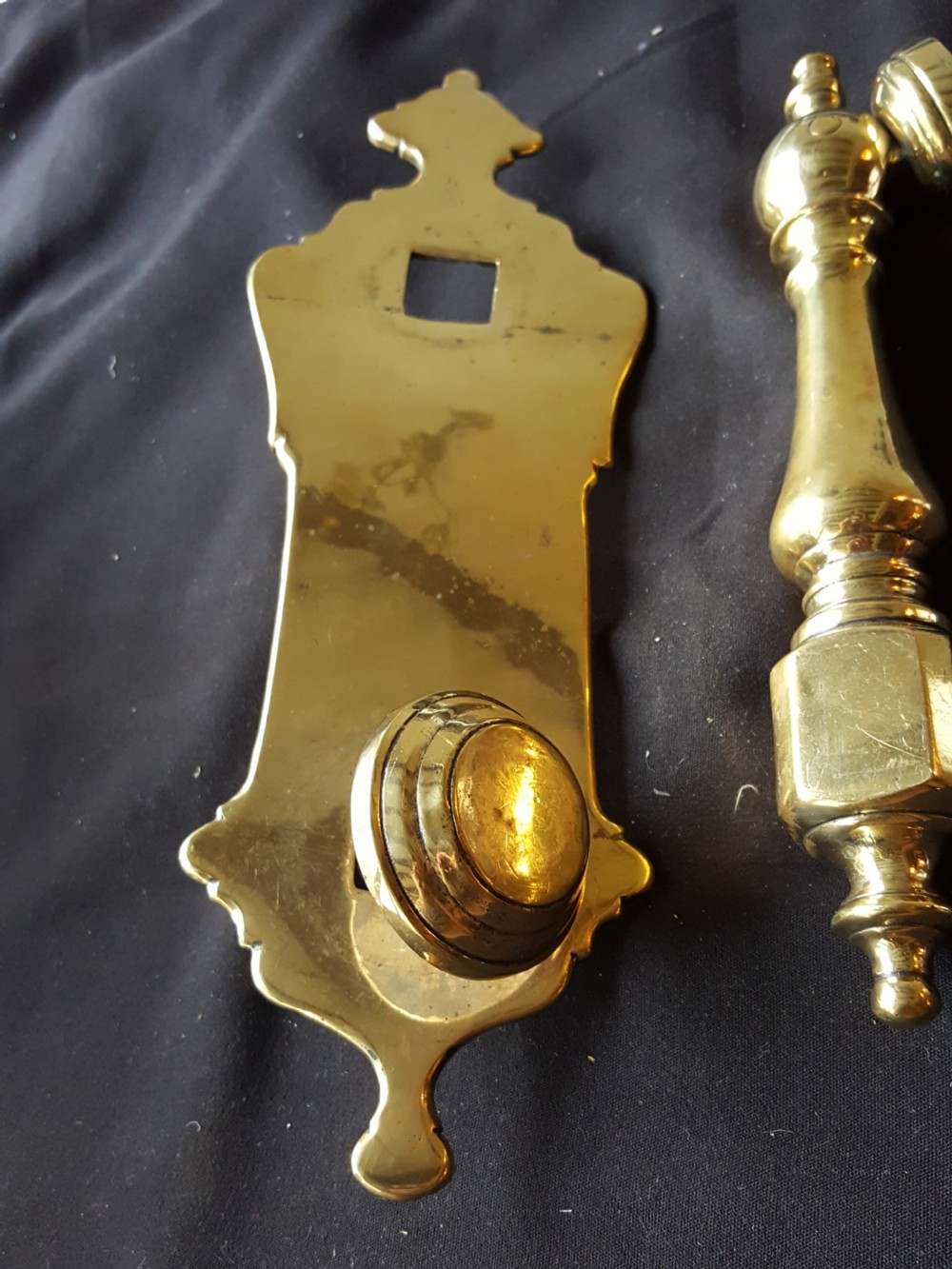A two-piece Victorian polished brass door knocker comprising a shaped backplate with a striking stud and a turned baluster-style knocker with a threaded bolt. View II