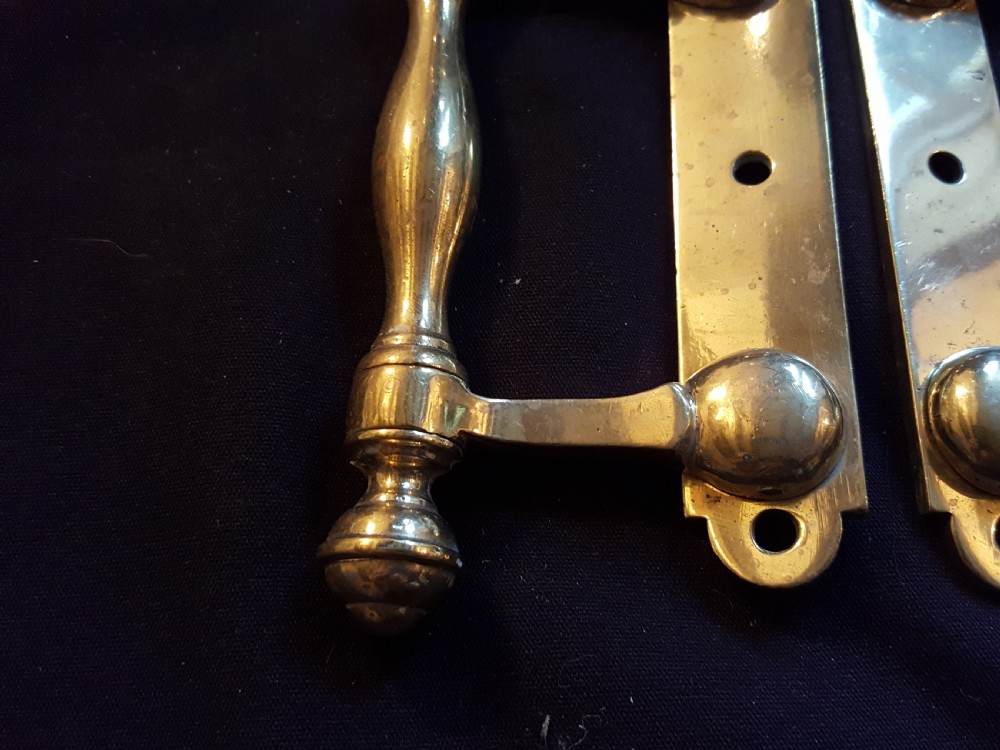 A pair of cast Victorian brass sash lifts featuring turned baluster handles with finials attached to flat mounting plates with screw holes. View II