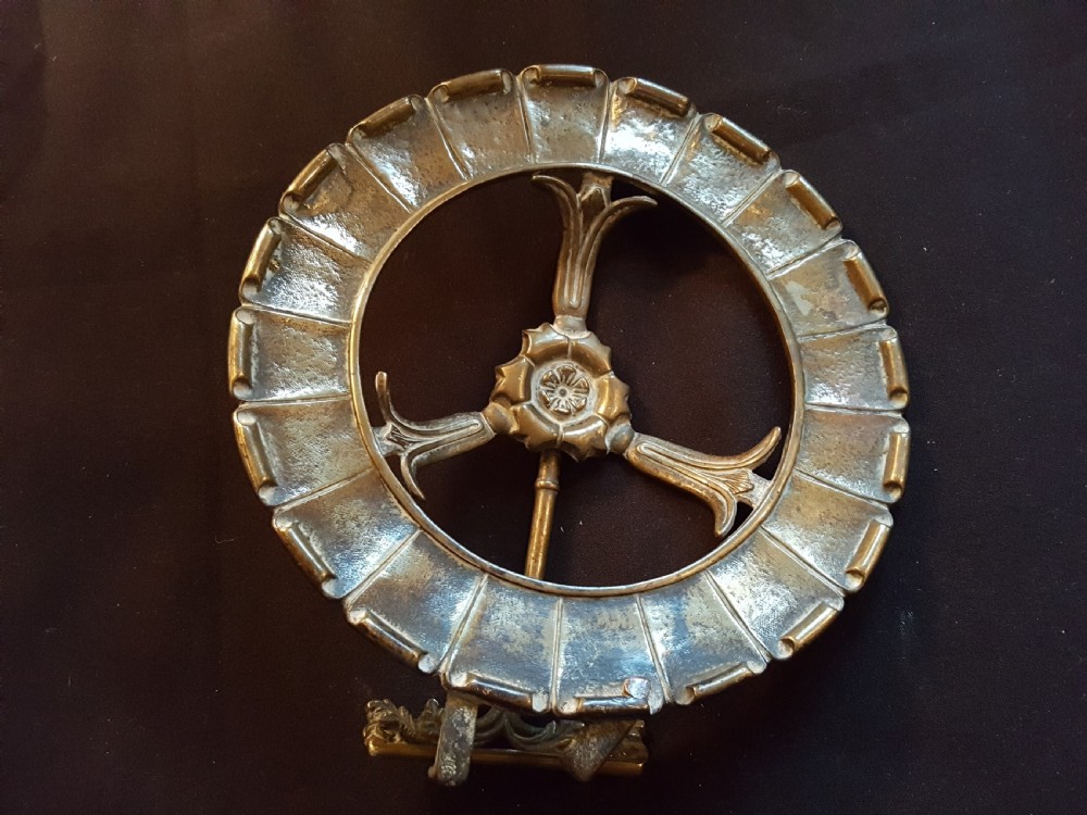 A circular Victorian brass kettle stand trivet featuring a fluted rim design and a central three-spoke motif.
