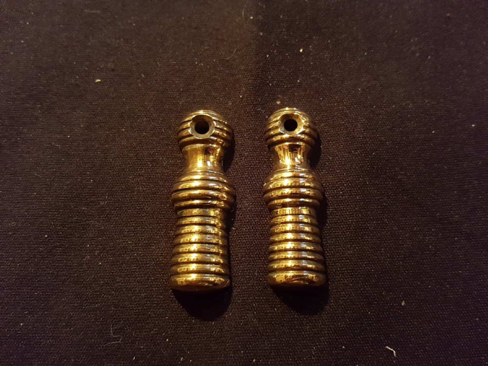 A pair of turned, polished brass keyhole escutcheons featuring a ribbed beehive design with a single mounting hole at the top.