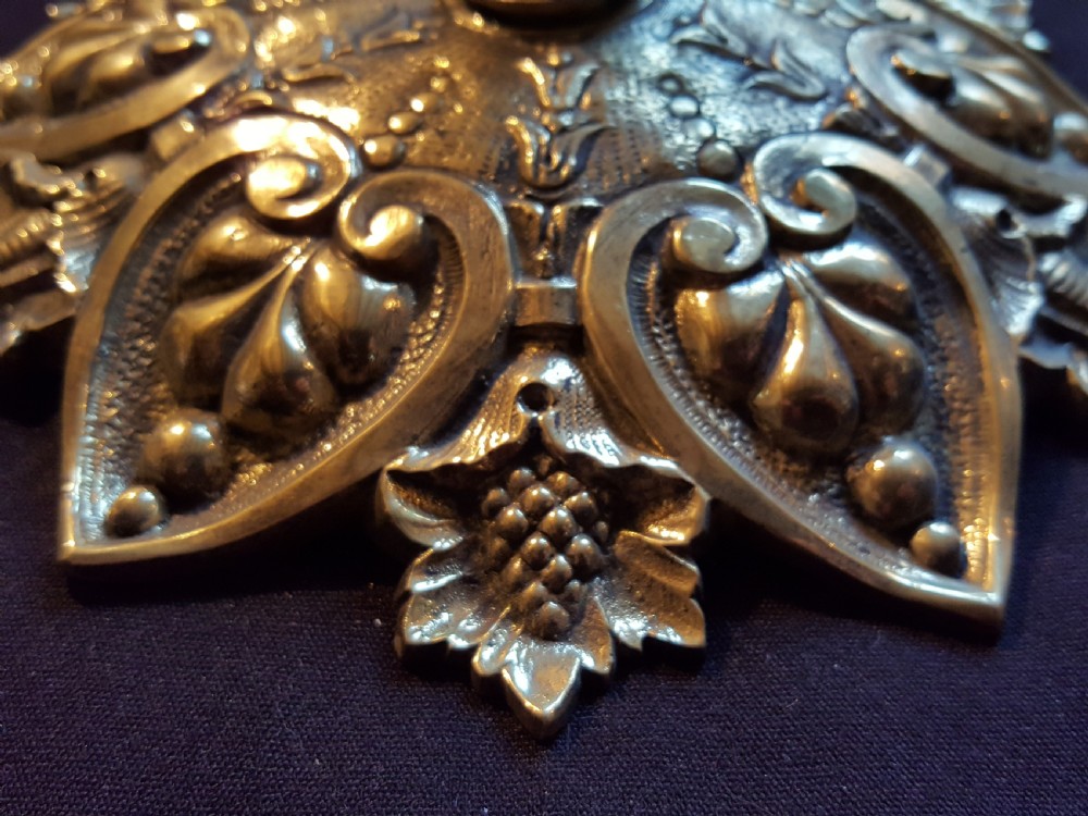 An ornate circular Victorian cast brass ceiling rose featuring relief foliage decoration and a central hanging hook. View II