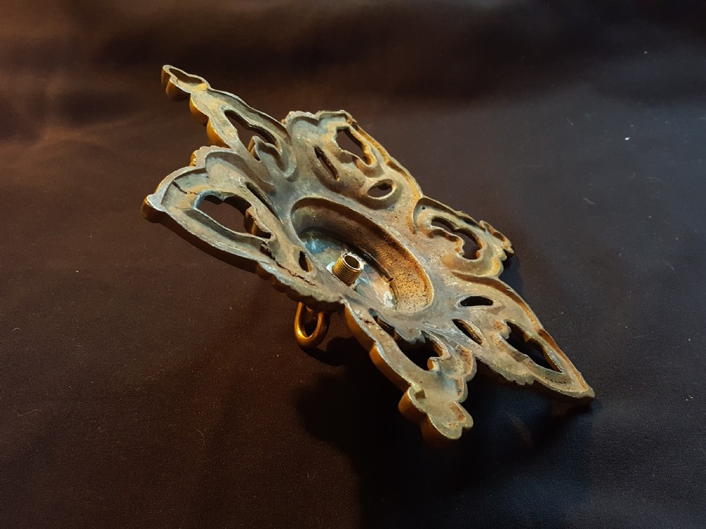 A Victorian cast brass ceiling rose featuring a central metal hook surrounded by openwork scrollwork and a starburst edge profile. View V
