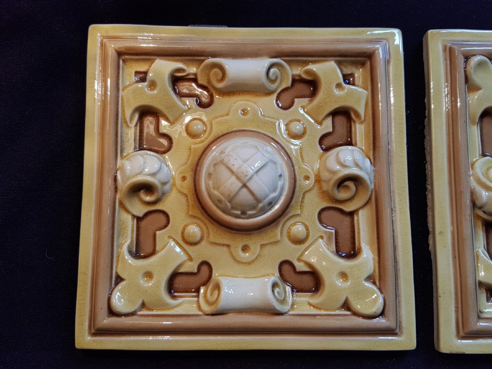 A set of six Victorian square earthenware tiles featuring high-relief moulded scrollwork and central cabochons in ochre and brown glazes. View II