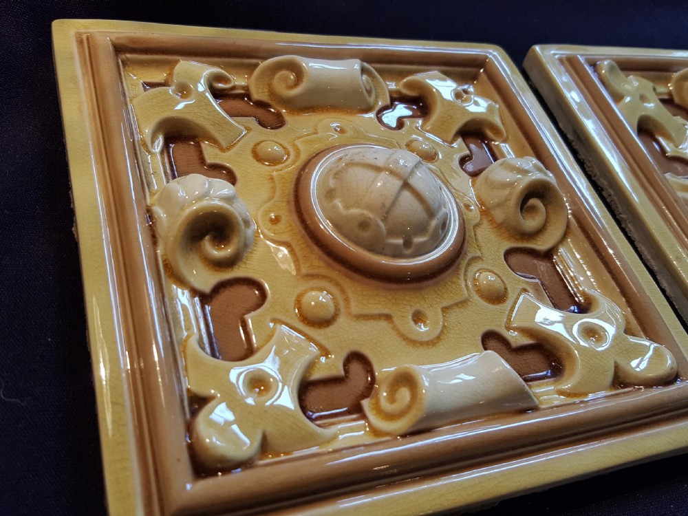 A set of six Victorian square earthenware tiles featuring high-relief moulded scrollwork and central cabochons in ochre and brown glazes. View IV