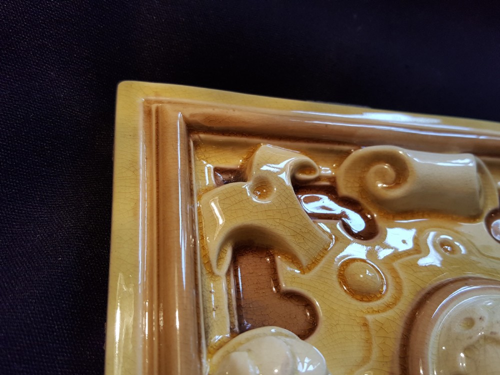 A set of six Victorian square earthenware tiles featuring high-relief moulded scrollwork and central cabochons in ochre and brown glazes. View V