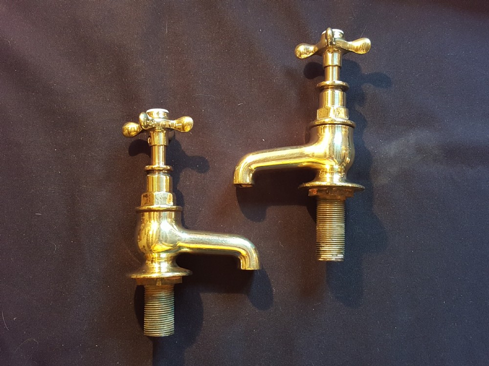 A pair of restored Victorian polished brass bath taps featuring crosshead handles and threaded tails.
