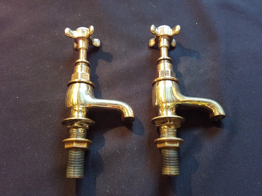 A pair of restored Victorian polished brass bath taps featuring crosshead handles and threaded mounting pillars.