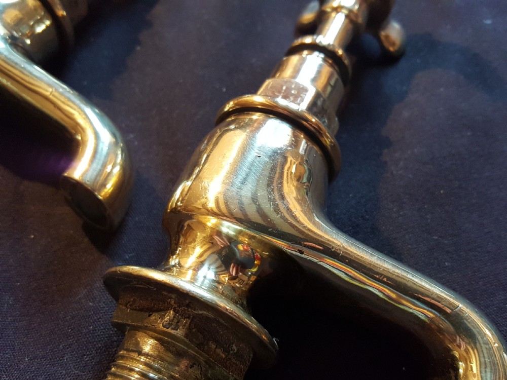 A pair of restored Victorian polished brass bath taps featuring crosshead handles and threaded mounting pillars. View V