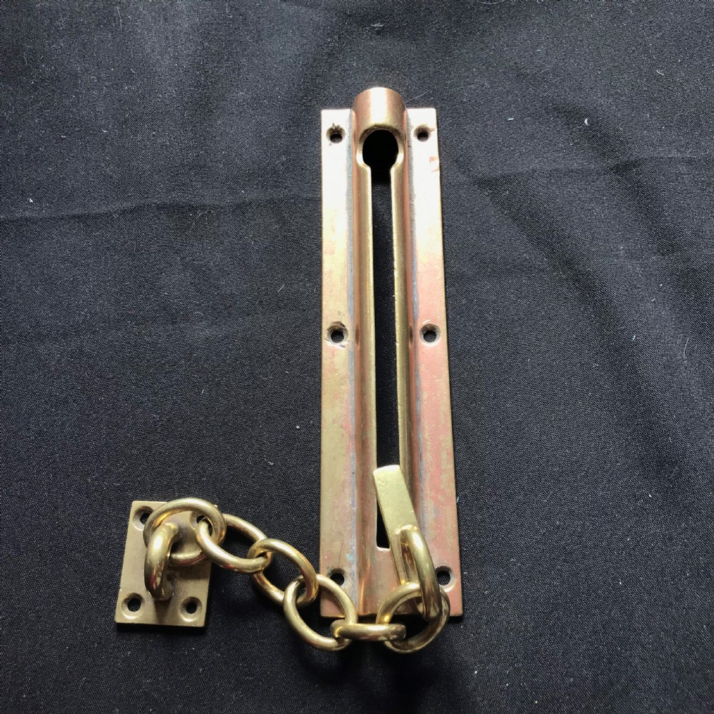 A solid brass Victorian night door chain featuring a slotted slider backplate, a small mounting plate, and connecting oval chain links.
