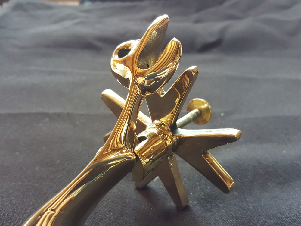 A polished brass door knocker shaped as a stylised dolphin mounted on a Maltese cross backplate alongside a separate brass striker button. View IV
