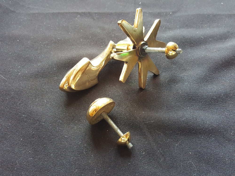 A polished brass door knocker shaped as a stylised dolphin mounted on a Maltese cross backplate alongside a separate brass striker button. View VI